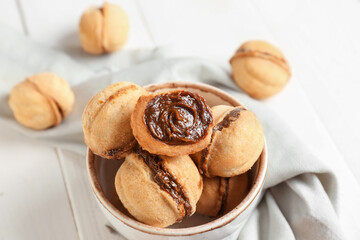 Wall Mural - Bowl with sweet walnut shaped cookies with boiled condensed milk on white wooden background