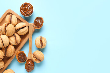 Wall Mural - Wooden board with sweet walnut shaped cookies with boiled condensed milk on blue background