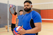 © Wavebreak Media - Diverse male teammates in sportswear holding volleyball, jumping near net in gym