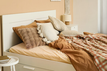 Wall Mural - Comfortable bed with pillows and blanket near beige wall in bedroom, closeup