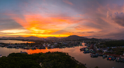 Wall Mural - Aerial view of Stunning sunset featuring fishing port in Phuket. The vibrant sky transitions from soft purples to fiery orange hues, creating a tranquil and picturesque atmosphere.