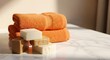 © Ronie - Stack of soft orange terry cloth towels and natural soap bars on a white marble counter, bathed in gentle sunlight, symbolizing fresh hygiene and self-care.