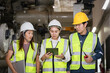 © Sumala - teamwork and industrial safety, Group of engineers and technicians wearing safety helmets and reflective vests inspecting high-voltage gas-insulated switchgear (GIS) inside a power plant