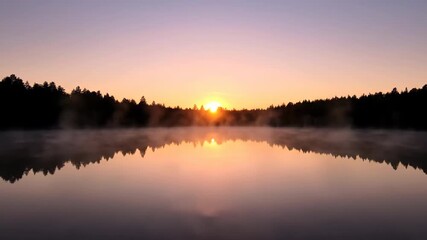 Wall Mural - The sun slowly rises over a calm lake, illuminating the misty surface and distant forest line outdoor, beautiful, timelapse