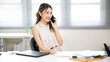 © bongkarn - Pretty woman office worker holding pen talking to a friend or coworker on phone at table in office.