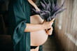 © Haseeb - Celebrate motherhood with a stunning display of a pregnant woman holding lavender in a cozy indoor setting
