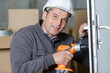 © auremar - worker using cordless screwdriver on door lock