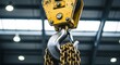 © ENDRA - Heavy duty industrial crane hook with thick metal chain hanging down, industrial workshop setting with bright overhead lights