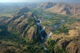 High-angle view of Victoria Falls, surrounded by rugged hills and lush vegetation