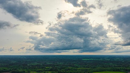 Wall Mural - Storm clouds gather and flow over sunny green landscape and open farmland, dramatic and moody lighting