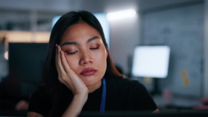Sleepy and Tired Asian Businesswoman Sitting at Desk with Laptop computer, Working Overtime. Exhausted Female Office worker struggling to stay awake, Feeling Fatigue, Stress While Working Overtime.