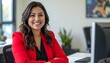 © Roberto - a smiling brunette woman with short hair wearing a red jacket and a black top sitting at the desk in the office