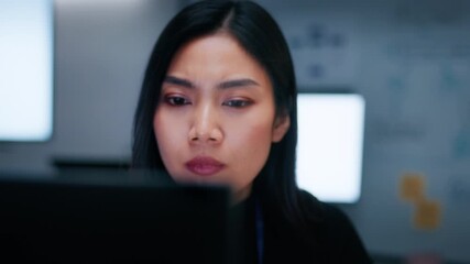 Professional Asian Female Software Engineer sitting at desk, looking at computer screen, hand typing on keyboard, writing code, developing software app, prompt ai machine learning data in office night