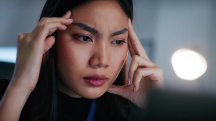 Close-up of Focused Asian Female Programmer looking at computer screen and Thinking about Problem Solving, Software Development, Reviewing Code and Planning a new business project at Desk in Office.