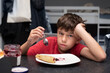 © Мар'ян Філь - A young, thin boy of ten years old sits in kitchen at home in front of plate of delicious pancakes with cottage cheese and jam. The boy is sad, does not want to eat, he has no appetite