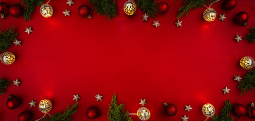 Wall Mural - christmas frame with green fir branches, red baubles, golden stars, and glowing string lights on a r