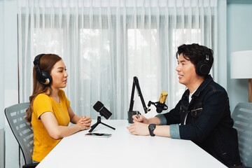 Smiling radio influencer host wearing headphone interviewing woman speaker sharing information to listeners on social media online website live streaming channel at morning at studio record. Infobahn.