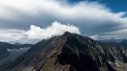 Wall Mural - time-lapse effect wide shot of fast-moving clouds casting shadows over a rugged mountain peak planet