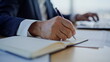 © stockbusters - Entrepreneur hand writing notebook at office desk closeup. Senior businessman