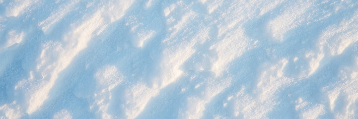 Wall Mural - Beautiful winter background with snowy ground. Natural snow texture. Wind sculpted patterns on snow surface. Wide panoramic texture for background and design.