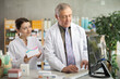 © JackF - Elderly male and young female pharmacists looking for pills on computer in pharmacy