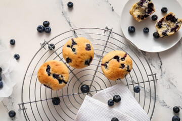 Wall Mural - Cooling rack and plate with tasty blueberry muffins on marble background