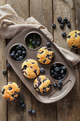 Wall Mural - Napkin and baking tray with tasty blueberry muffins on wooden background
