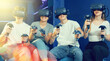 © JackF - Group of excited young people with handheld controllers in hands engaged in virtual world experiencing through VR glasses covering face. Concept of immersion and interactivity in game