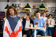 © JackF - Company of young adult sports supporters with national flag of England upset about favorite team losing match in bar
