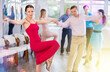 © JackF - Happy young adult woman enjoying active dancing in pair with male partner during group training in dance studio. Social dancing concept..