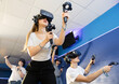 © JackF - Young woman with handheld controllers in hands clearly excited and engaged in virtual world experiencing through VR glasses covering face. Concept of immersion and interactivity in game