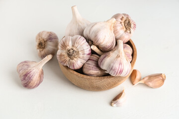 Wall Mural - Wooden bowl with fresh garlic and cloves on white background