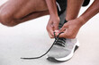 © New Africa - Runner tying shoelace of his sneaker outdoors, closeup