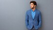 © pinporn manosri - Elegant young male in smart attire, posing confidently against a gray background, showcasing modern fashion trends for men's wear in professional contexts.
