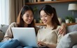 © wu - Two asian young woman happy smiling and using computer laptop on couch in living room at home. High quality