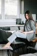 © Darius - Young woman reading a magazine while sitting on a kitchen counter in modern space