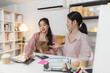 © Imagestoyou - Two young women work together in a small business office, organizing packages, checking financial reports, and managing orders on digital devices, representing teamwork and entrepreneurship.