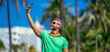 Tourist takes a selfie near palm tree. Man captures a selfie during summer vacation. Traveler snaps a selfie in a tropical destination. A selfie with palm trees captures the tropical vibes.