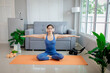 © Pang - Young woman practicing yoga indoors, sitting in lotus position with calmness, balance, and focus, promoting health, relaxation, and wellness.