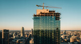 Modern skyscraper construction with crane against clear blue sky at sunset
