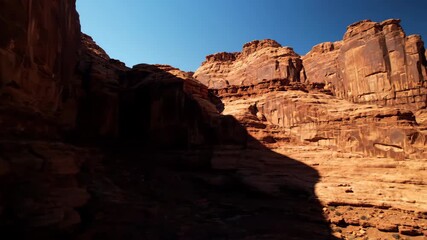 Wall Mural - slow pan across ancient, rugged rock formations with dramatic shadows under harsh light wilderness, 
