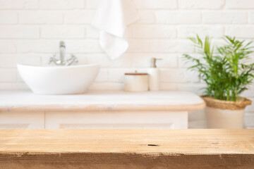 Wall Mural - Aged lightly lit wooden table top in front of rustic blurred bathroom interior background