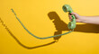 © ABIR HASAN - A hand holds a vintage green rotary telephone handset with a coiled cord against a vibrant yellow background casting a long shadow evoking retro communication and nostalgia