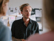 © midl - Ritratto di un uomo d'affari con barba e tatuaggi durante una discussione creativa in ufficio, un concetto di leadership e innovazione