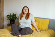 © mdyn - Positive redhead 30s woman sitting in bed and smiling to camera at home