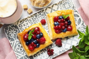 Wall Mural - Tasty puff pastries with berries, mint, brown sugar and coffee on light grey table, flat lay
