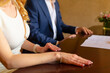 © Alena - A couple sits closely together at a table, ready to officially sign important legal documents that symbolize their formal partnership agreement