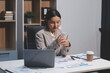 © Sutthicha - Positive asian young female accountant using a smartphone at her office desk. Woman relaxing on her mobile application.