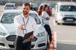 © standret - Documents in hands of a guy. Man instructor in the driving school and woman are outside the car