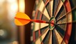 © miss irine - Close-up orange dart hits bullseye on dartboard in soft focused sunlight. Accurate shot, direct hit. Target achieved, aim success, competition win. Game of darts on sunlight background.